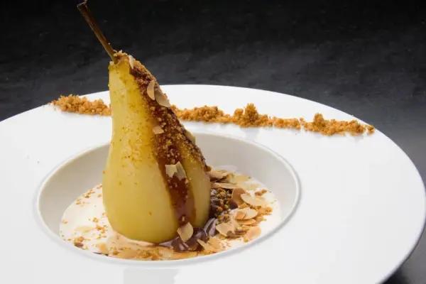 Un poire pochée, nappée de chocolat et amandes effilées, servie avec une crème légère. Un dessert poire chocolat rapide et gourmand.
