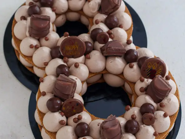 Gâteau number cake chocolat, décoré de crème onctueuse, de chocolats et de billes croquantes. Parfait pour une recette number cake chocolat d'anniversaire.